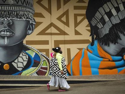 Una madre pasea con su hijo junto a unos grafitis en las calles de Johanesburgo (Sudáfrica). 