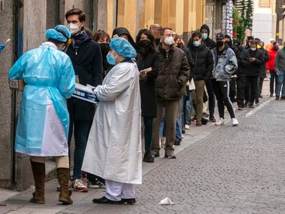 Personal sanitario atiende a personas haciendo cola para una PCR frente al centro de salud Universidad en Malasaña (Madrid).