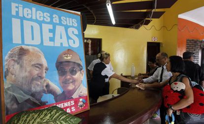 Un grupo de personas compran productos en una tienda que muestra un cartel alusivo a Fidel Castro y a su hermano, el presidente de Cuba, Fidel Castro, mientras esperan la llegada de la caravana que traslada las cenizas del fallecido líder de la revolución cubana Fidel Castro, en Holguín, a 800km de La Habana (Cuba).