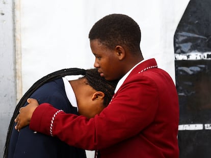 Dos estudiantes se consuelan durante el funeral por los 21 menores de edad hallados muertos en una discoteca para adultos, el 6 de julio de 2022 en East London, Sudáfrica.