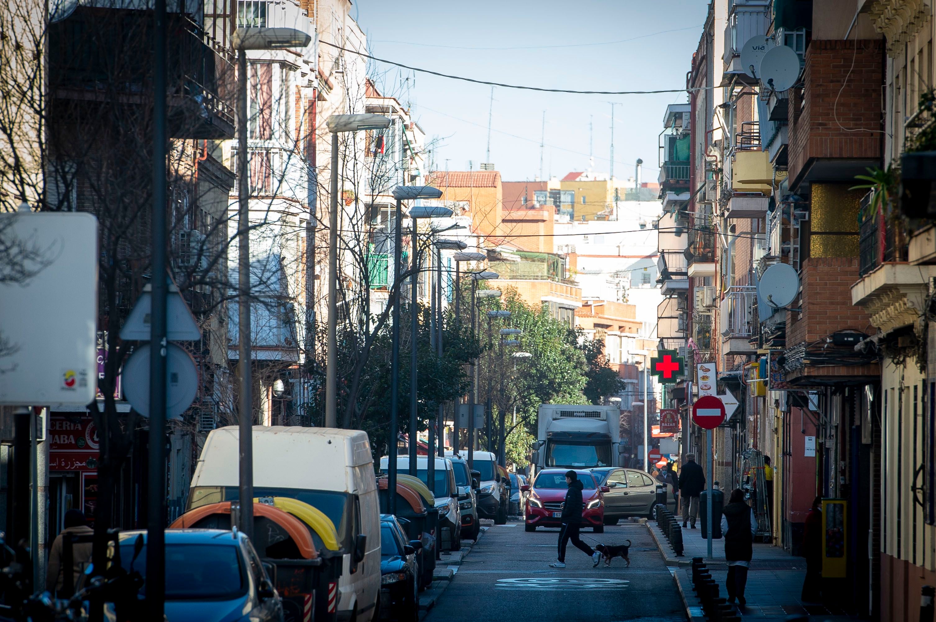 Un joven cruza la calle con un perro en la Avenida Monte Igueldo, en el distrito de Puente de Vallecas.