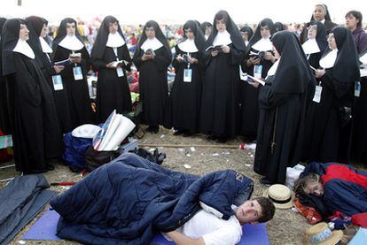 Un grupo de religiosas rezan junto a dos peregrinos al amanecer de la vigilia de Cuatro Vientos.