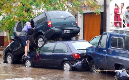 Un hombre sube a un vehículo en una calle inundada de la ciudad La Plata (Argentina).