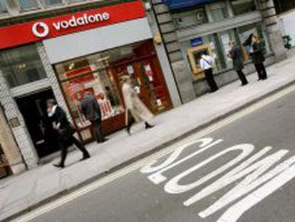 Varias personas pasean junto a una tienda de Vodafone.