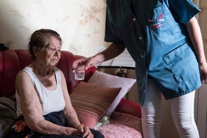 Una cuidadora le da un vaso de agua a una persona mayor durante una visita para ayudar a evitar golpes de calor y deshidratación durante la ola de calor, el 25 de junio de 2019, en Clermont-Ferrand, Francia.