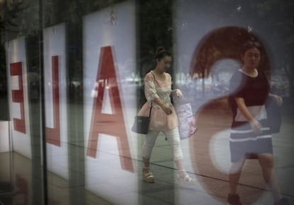 Dos mujeres, reflejadas ante unos almacenes en rebajas, en Pek&iacute;n.