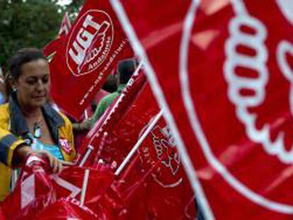 Una mujer prepara las banderas de los sindicatos en una concentración. EFE/Archivo