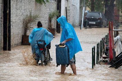 Un hombre y una mujer caminan entre las calles de Volos, que ha sufrido importantes inundaciones, este martes en Grecia. 