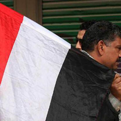 Un hombre con una bandera egipcia, delante de una tienda en la plaza cairota de Tahrir pintada con la palabra Twitter.
