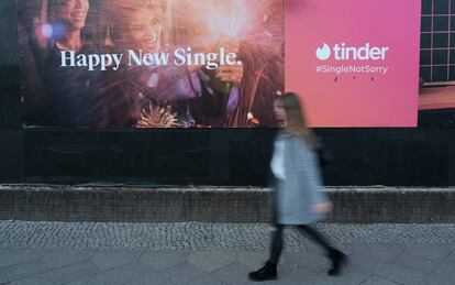Una mujer pasa frente a un cartel de la aplicación de citas Tinder.