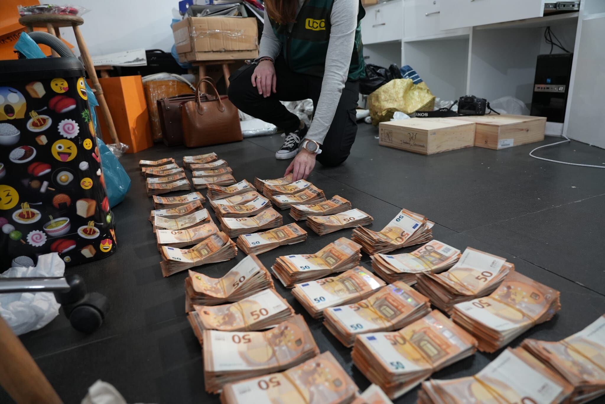 Un agente de la UCO de la Guardia Civil apila billetes intervenidos tras los registros de este lunes en la Operación Guanxi.