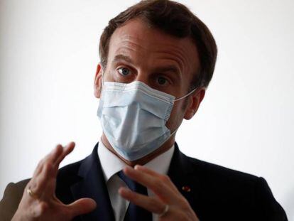 El presidente francés Emmanuel Macron protegido por una máscara facial habla con trabajadores sanitarios en una visita a un centro médico de Paris