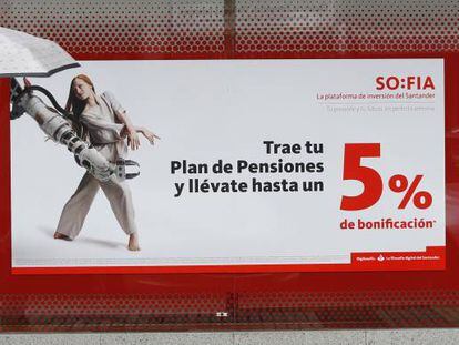 Una mujer pasa delante de un anuncio de planes de pensiones, en una oficina de Banco Santander, en Madrid.