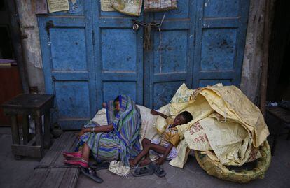 Una madre y su niño descansan sobre sus pertenencias a la sombra de un edificio en Nueva Delhi, India. 11 de junio 2014.