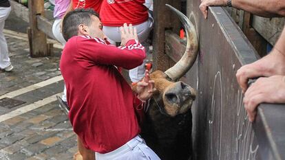 Un toro de Pedraza de Yeltes embiste a un mozo en el cuarto encierro de San Fermín 2016.