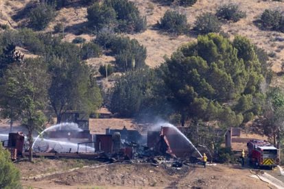 Firefighters throw water on the remains of the property of the alleged murderer of Agua Dulce.