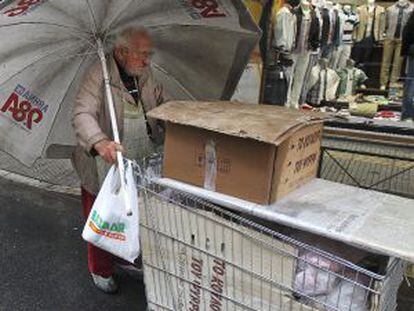 Un vendedor callejero empuja su carrito bajo la lluvia en Atenas.