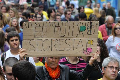 Estudiantes y maestros se manifiestan por las calles de Barcelona. Una mujer sostiene una pancarta donde se lee "El futuro secuestrado".