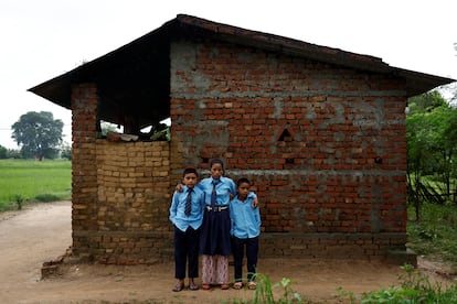 Parwati Sunar, de 27 años, y sus hijos, Resham Sunar, de 11, y Arjun Sunar, de siete, posan para una foto después de vestirse para acudir a la escuela, fuera de su casa en Punarbas, distrito de Kanchanpur, suroeste de Nepal, este 7 de agosto.