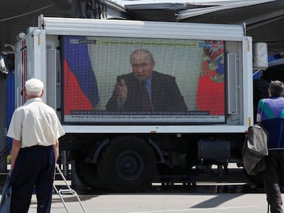 Dos ciudadanos ven un mensaje televisado de Putin en una calle de Mariupol.