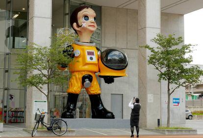 Una mujer toma una fotografía de la escultura gigante del niño con traje antirradiación, 'Sun Child', en Fukushima (Japón).