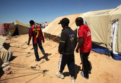 Tres refugiados etíopes, caminan en un campo de acogida del ACNUR, en Túnez, en la frontera con Libia.