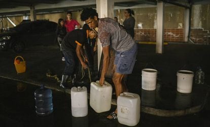 Vecinos de la urbanización El Encantado, en Caracas, llenan recipientes de agua.