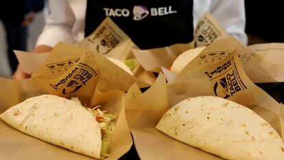 Un empleado de Taco Bell muestra una bandeja llena de tacos.