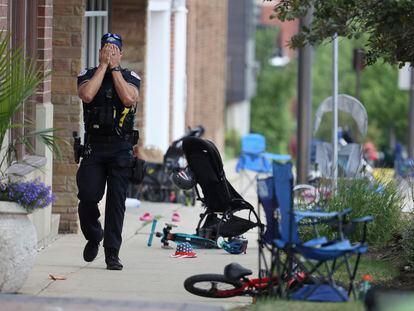 CORRECTS TO A LAKE FOREST POLICE OFFICER, INSTEAD OF LAKE COUNTY A Lake Forest, Ill., police officer walks down Central Ave in Highland Park, Ill., on Monday, July 4, 2022, after a shooter fired on the northern suburb's Fourth of July parade. (Brian Cassella/Chicago Tribune via AP)