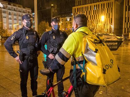 Dos policías informan a un repartidor sobre la aplicación del toque de queda la noche del domingo en Zaragoza.