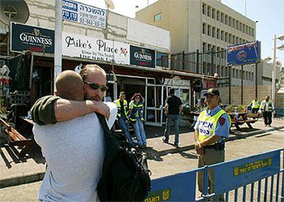 El dueño de la cafetería de Tel Aviv víctima del atentado (con gafas) se abraza a un amigo tras el atentado. 

/ AP