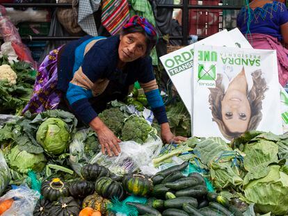 Una vendedora junto a una imagen publicitaria en un mercado de Guatemala.