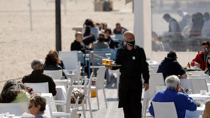 Un camarero atiende las mesas de una terraza de un bar en la playa de la Malvarrosa, en Valencia.