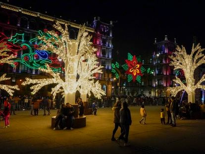 Personas caminan entre decoraciones festivas en el Zócalo de la capital mexicana, en diciembre de 2021.