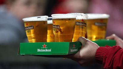 Un consumidor carga una bandeja con varias cervezas Heineken.