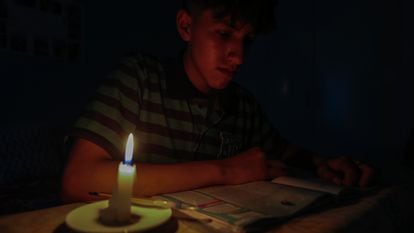 Un estudiante lee un texto a la luz de una vela en Quito, Ecuador.