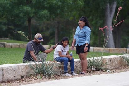 A girl cries, comforted by two adults, outside the Willie de Leon Civic Center, where grief counseling is offered in the Uvalde community.