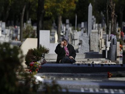 Una mujer llora frente a la lápida de un familiar en el cementerio madrileño de La Almudena. 