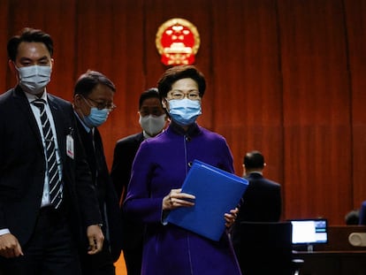 La jefa del Gobierno autónomo de Hong Kong abandona el hemiciclo del parlamento del territorio autónomo. Al fondo, el emblema de la República Popular de China