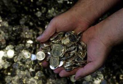 Un empleado de la Casa de la Moneda sostiene monedas de un euro. EFE/Archivo