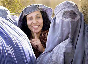Una viuda afgana sonríe al levantarse el <i>burka</i> mientras aguarda su ración del Programa Alimenticio de la ONU.