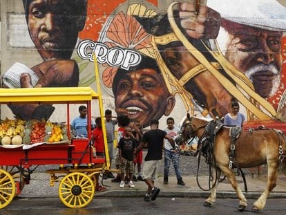Unos niños alrededor de un carro tirado por caballos con productos para la venta ambulante, en Baltimore (EE UU).