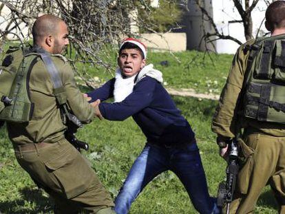 Un manifestante palestino vestido de Pap&aacute; Noel (centro) se enfrenta a un soldado israel&iacute; en una protesta cerca de Nablus.