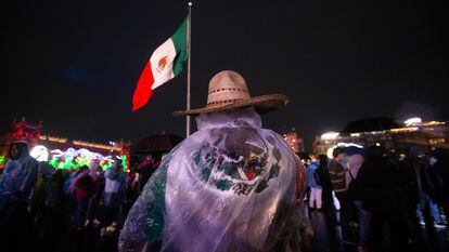 Un hombre se protege de la lluvia con una bandera en el Zócalo de Ciudad de México.