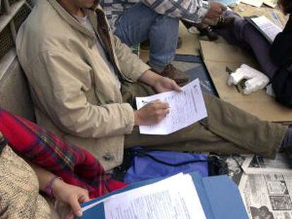 Inmigrantes rellenan sus papeles para entregarlos en una oficina de la Delegación del Gobierno de Madrid.