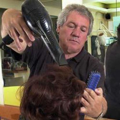 Un peluquero peina a una señora en su peluquería