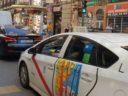 Un taxi y un vehículo con licencia VTC, en Madrid.