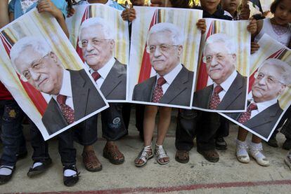 Un grupo de niños palestinos sostiene carteles con la cara del presidente palestino, Mahmud Abbas, en Azmut, en Cisjordania.