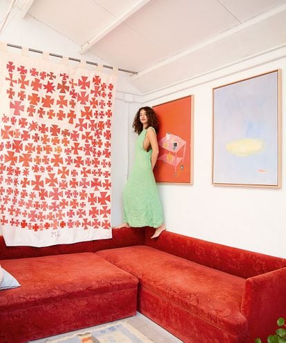 Clara Cebrián on her sofa, with some of her paintings.