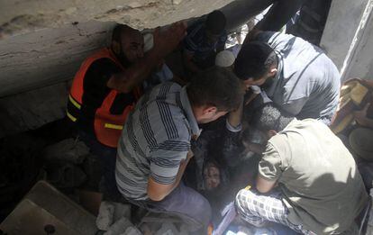 Personal de rescate ayudan a sacar el cuerpo de una mujer entre los escombros de su vivienda en Gaza, el 30 de junio de 2014.